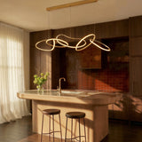 The loops lit above a kitchen island with two stools, curtains and a plant