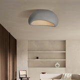 Textured dome ceiling light lit in a room with built in shelving and a pale wall