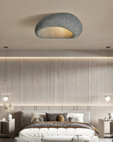 Textured dome ceiling light in a bedroom with long curtains and a low bed