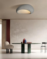Textured dome ceiling light above a dining area with a green table and a stool