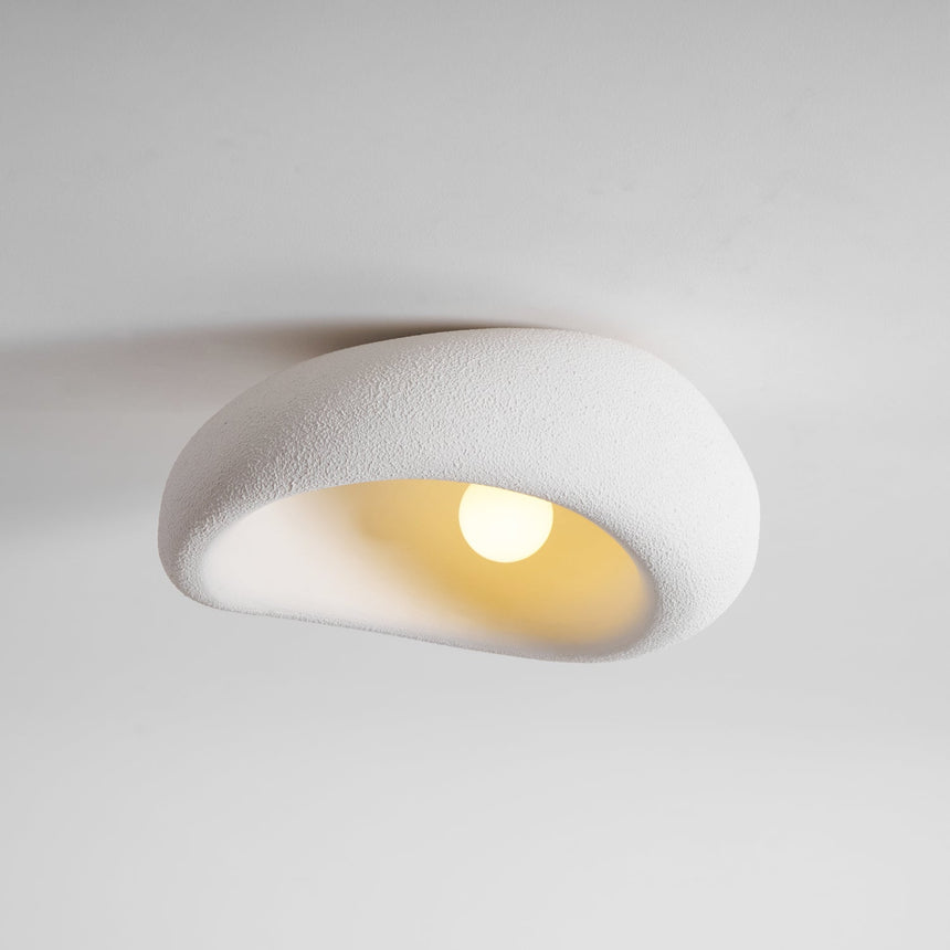 Textured dome ceiling light lit, seen from the side against a pale wall