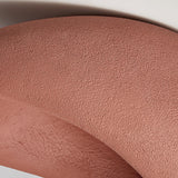 Close view of the brick red textured surface curving away from the opening