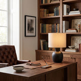 Sphere base lamp lit on a desk in a study lined with bookshelves