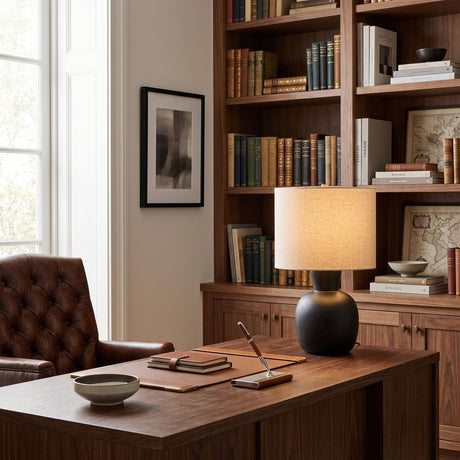 Sphere base lamp lit on a desk in a study lined with bookshelves