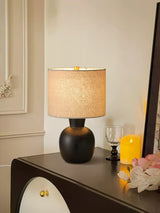 Sphere base lamp lit on a console beside a glass and a candle