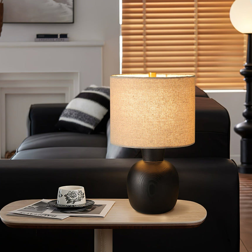 Sphere base lamp lit on a side table beside folded magazines
