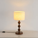 Round table lamp lit close up, the shade bright above the wood spheres
