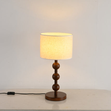 Round table lamp lit close up, the shade bright above the wood spheres
