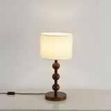 Round table lamp lit and seen at a three quarter angle beside a wall