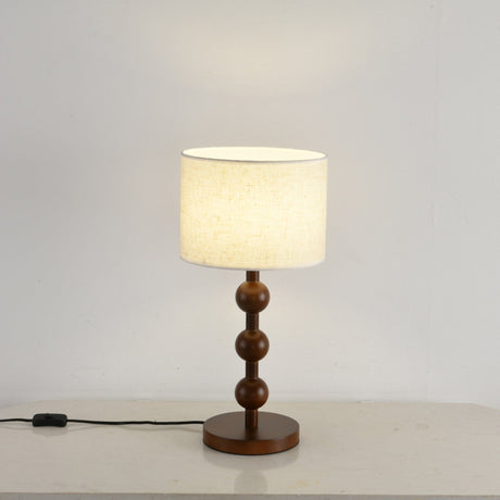 Round table lamp lit and seen at a three quarter angle beside a wall