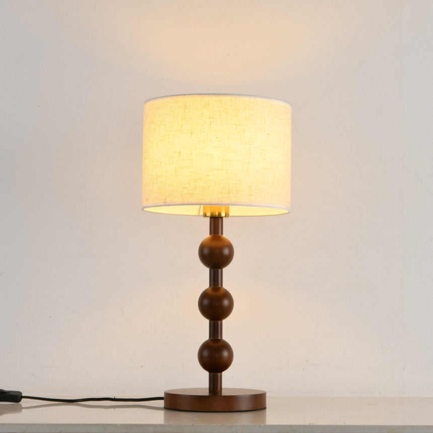 Round table lamp lit with a warm glow spreading up the wall behind