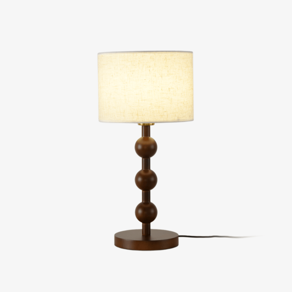 Round table lamp with stacked wood spheres under a white drum shade, plain background