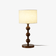 Round table lamp with stacked wood spheres under a white drum shade, plain background