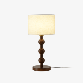 Round table lamp with stacked wood spheres under a white drum shade, plain background