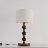 Round table lamp unlit and seen from the front, spheres and linen shade