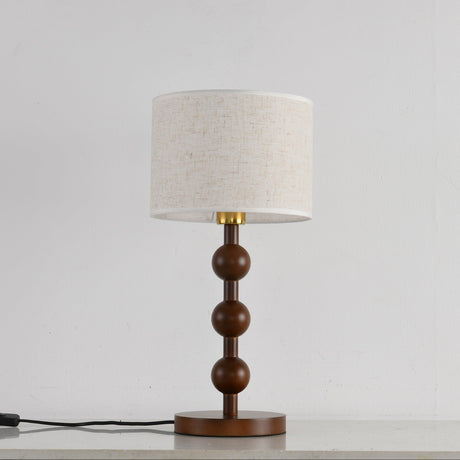Round table lamp unlit and seen from the front, spheres and linen shade