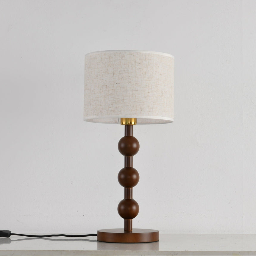 Round table lamp unlit and seen from the front, spheres and linen shade