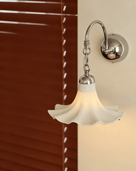The ruffled shade lit beside red wood blinds, its scalloped edge glowing