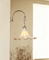 The ruffled sconce on a pale pillar beside a bright window and a dried branch