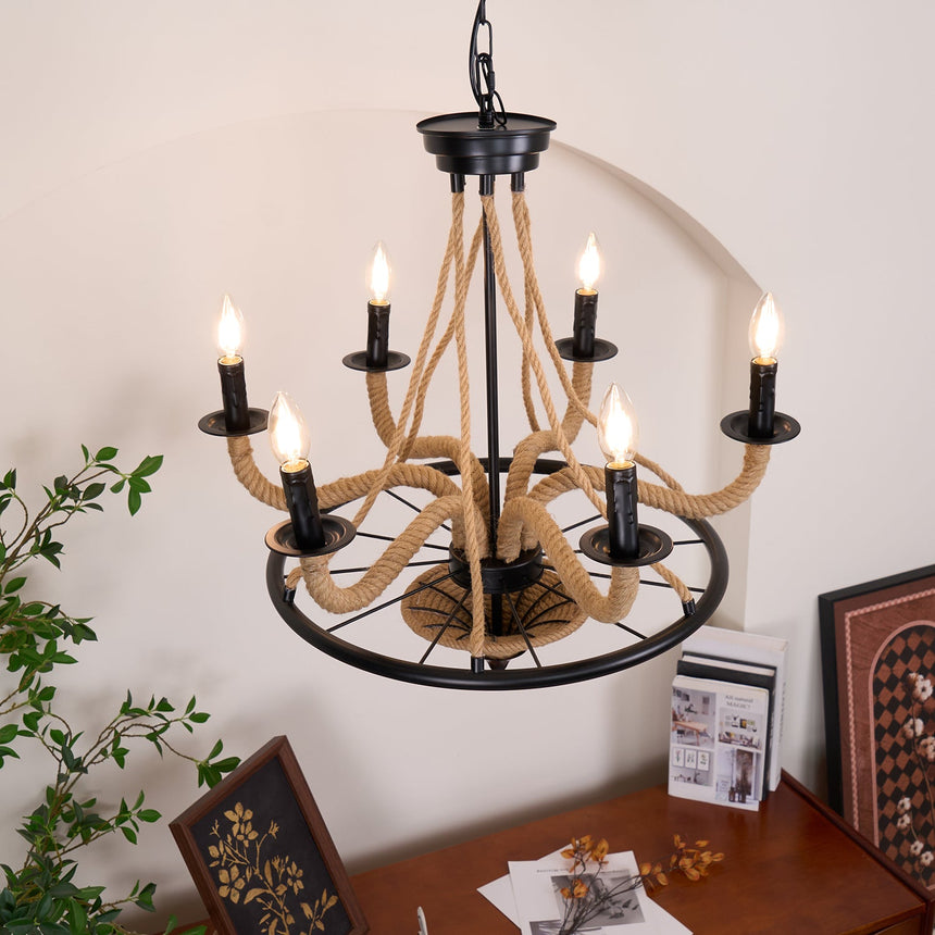 Chandelier lit next to a tall plant and a framed picture on the wall