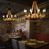 Two of the chandeliers lit above a long table in a brick walled room