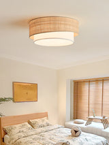 Two tier raffia ceiling light above a bed with a yellow framed print and shutters