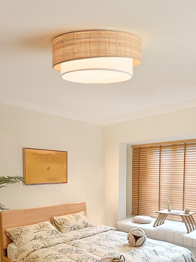 Two tier raffia ceiling light above a bed with a yellow framed print and shutters