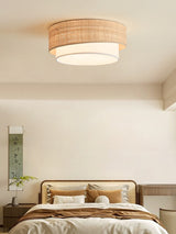Two tier raffia ceiling light in a bedroom with a wood bed and a tall plant
