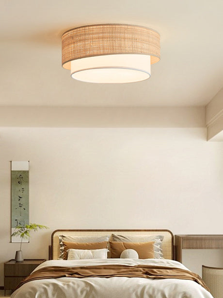 Two tier raffia ceiling light in a bedroom with a wood bed and a tall plant