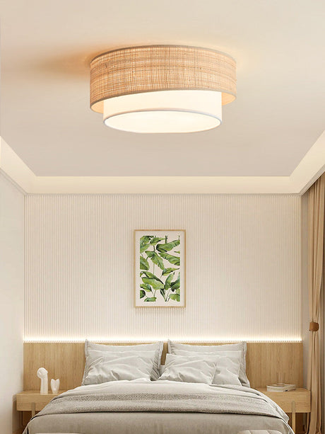 Two tier raffia ceiling light above a bed with a botanical print and slatted paneling