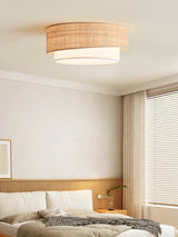 Two tier raffia ceiling light in a bedroom with a knitted throw and sheer curtains
