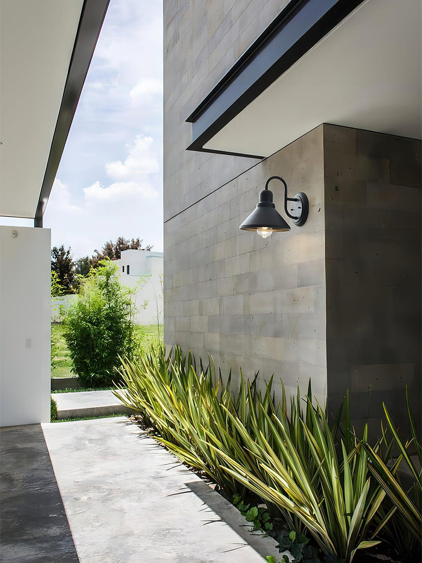 The light on a gray block wall above a planted border and a paved path