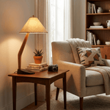 Rustic table lamp lit on a side table beside an armchair and a bookcase