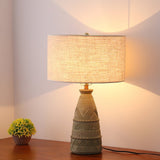 Rustic table lamp lit in a corner beside a small potted plant on wood