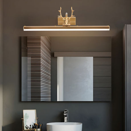 Gold antler bar lit above a mirror in a dark bathroom with a round stone basin