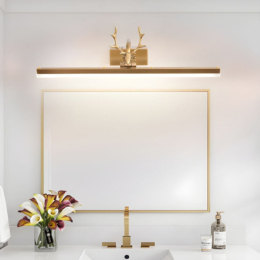 Gold antler bar lit above a framed mirror on a vanity with flowers and a tap
