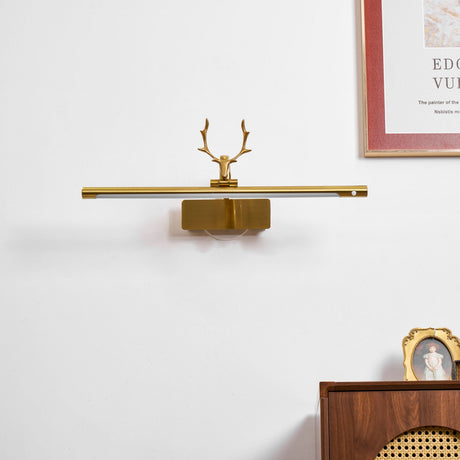 Gold bar lit above a cane fronted dresser with framed pictures and a cup