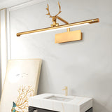 Gold bar lit on a white wall above a stone vanity with framed art leaning beside it