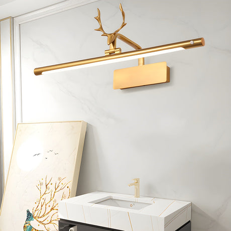 Gold bar lit on a white wall above a stone vanity with framed art leaning beside it