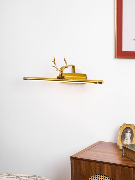 Gold bar lit above a walnut cabinet with small framed pictures and a marble table