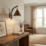 Sconce lit above a console table with framed pictures leaning on it