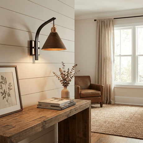 Sconce lit above a console table with framed pictures leaning on it
