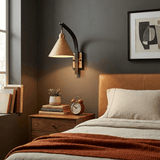 Sconce lit above a nightstand beside a bed against a dark wall