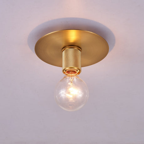 Brushed brass disc ceiling light lit at an angle on a plain ceiling