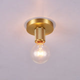 Brushed brass disc ceiling light lit and seen close against plaster