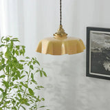 Beige scalloped shade lit beside a trailing green plant and a framed print
