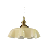 Beige scalloped glass shade with a brass top on a plain white background