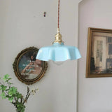Blue scalloped shade beside a gilt framed picture on a pale wall