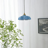 Blue scalloped shade between a trailing plant and a framed black print