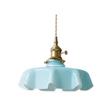 Blue scalloped glass shade with a brass top on a plain white background